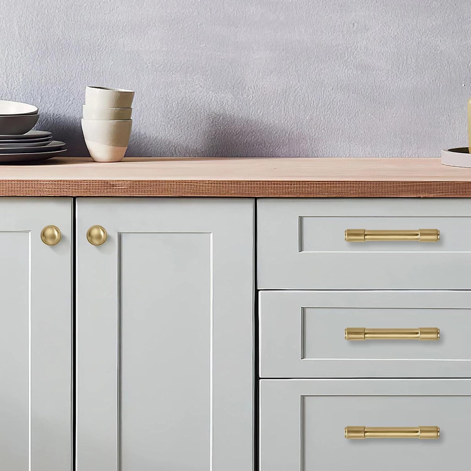 Brushed brass cabinet hardware installed on light gray kitchen cabinets